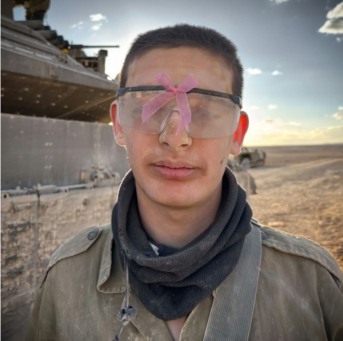 A soldier wearing safety goggles with a pink ribbon